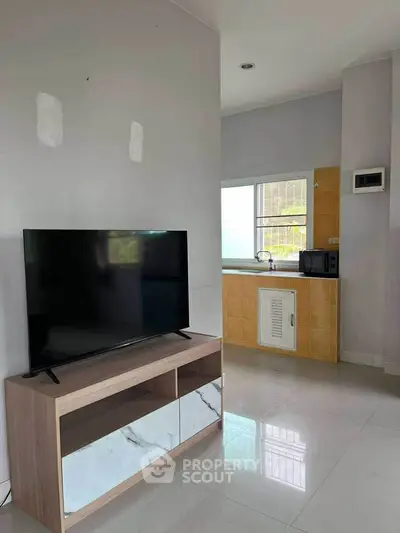 Modern living room with sleek TV stand and adjacent kitchen area.