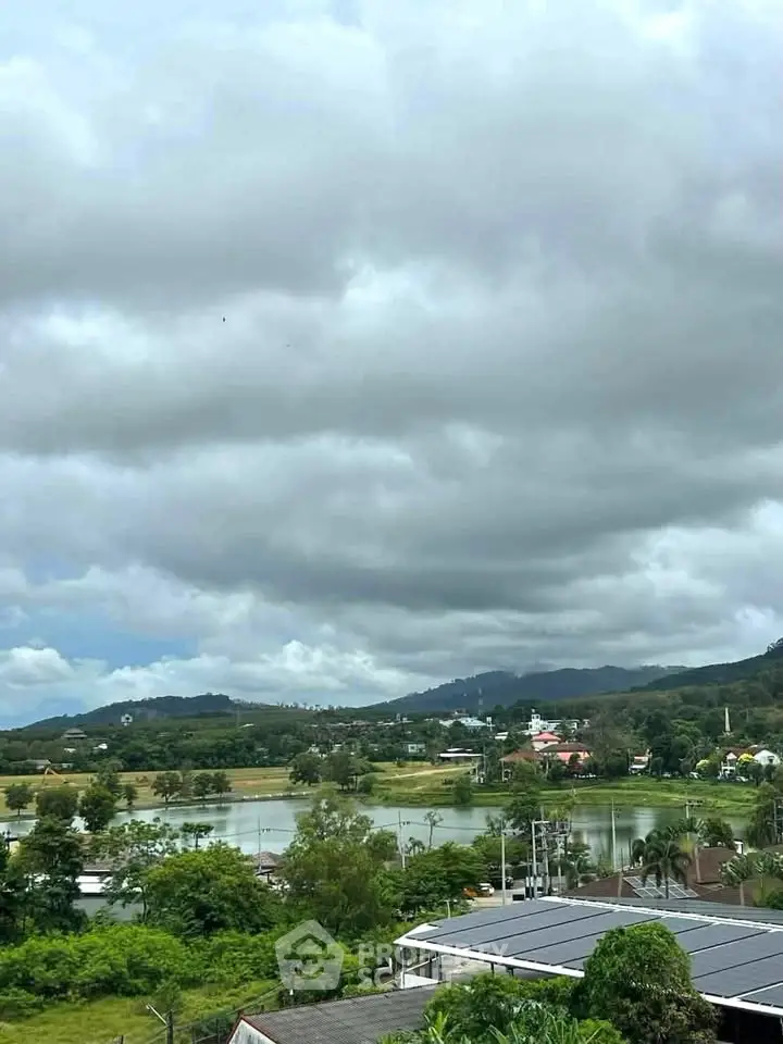 Scenic view of lush green landscape with hills and cloudy sky, perfect for serene living.