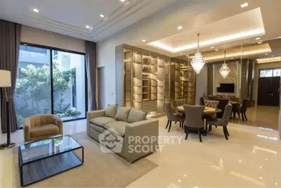 Luxurious living room with elegant chandelier and spacious dining area, featuring modern furniture and large windows.