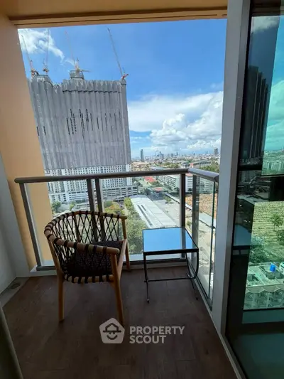 Modern balcony with city view, featuring stylish chair and glass railing, perfect for relaxation.