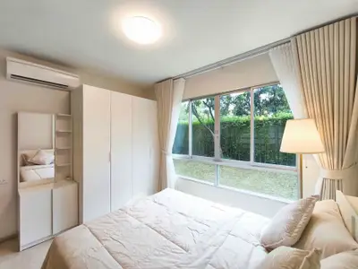 Bright and cozy bedroom with large window and garden view, featuring modern furniture and elegant curtains.