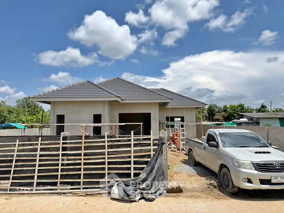 Modern single-story house under construction with a tiled roof and a pickup truck parked outside.