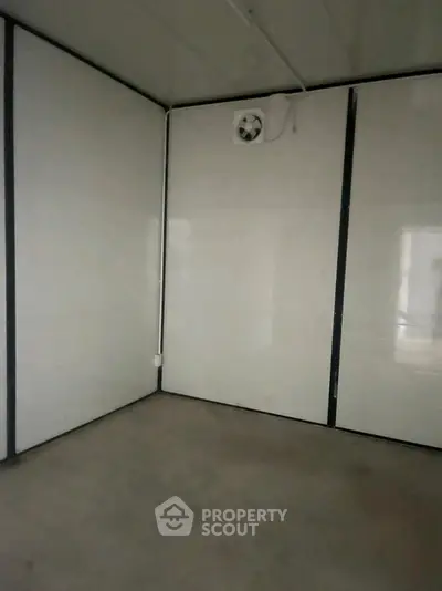 Minimalist interior space with white paneled walls and ceiling fan, ideal for versatile use.