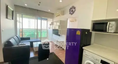 Modern living room with open kitchen, featuring sleek furniture and vibrant purple fridge.