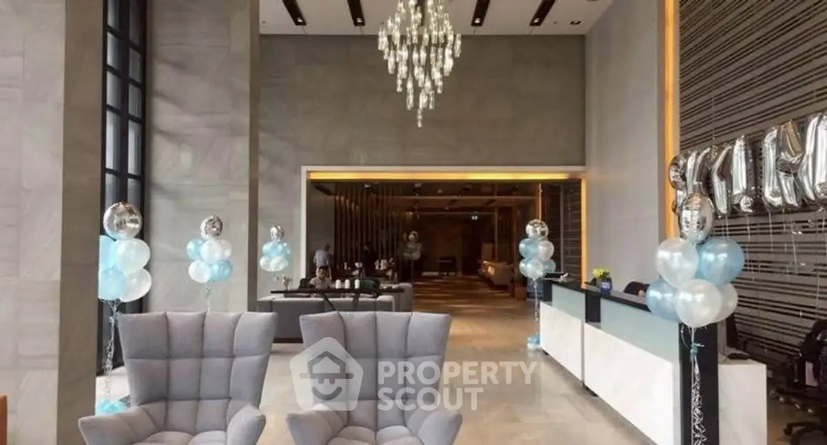 Luxurious lobby with elegant chandelier and modern seating in upscale building.