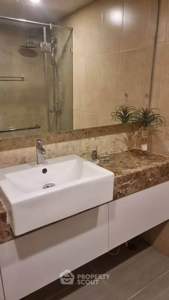 Elegant bathroom with modern sink and marble countertop, featuring a stylish shower area.