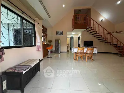 Spacious living room with modern staircase and dining area in a stylish home