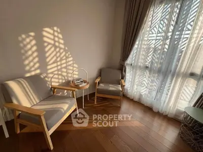 Cozy living room with elegant wooden flooring and stylish furniture, bathed in natural sunlight through large windows.