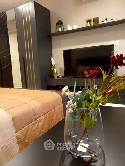 Stylish bedroom with modern decor and elegant furnishings, featuring a sleek TV setup and decorative plants.