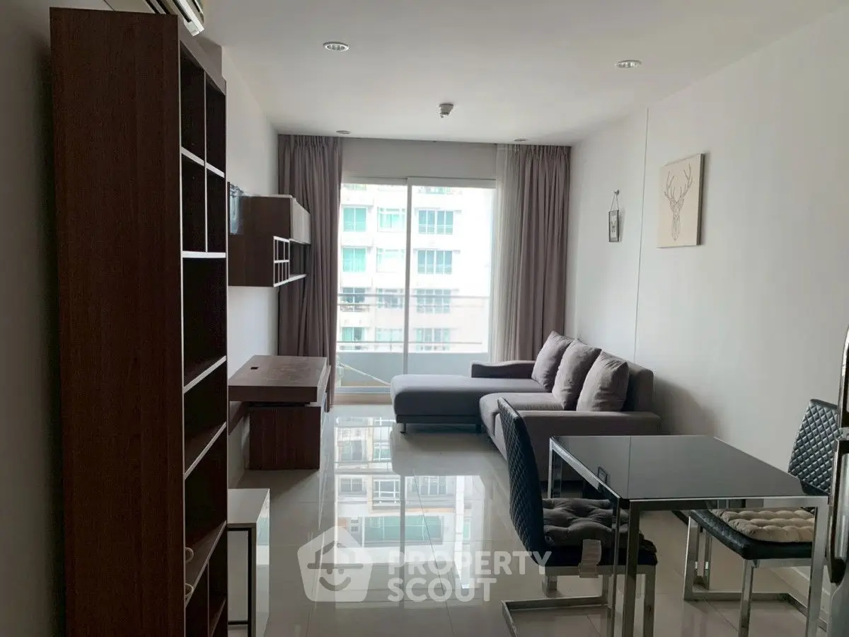 Modern living room with sleek furniture and large window offering natural light.