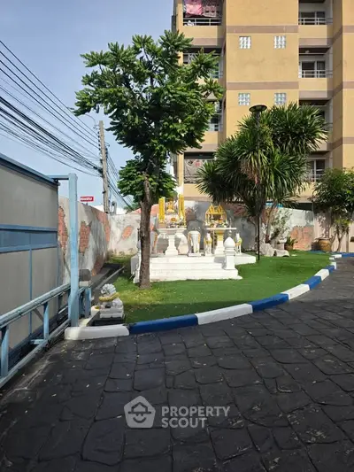 Charming apartment building exterior with lush greenery and decorative statues.