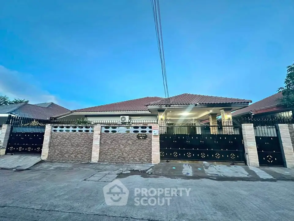 Charming single-story home with gated entrance and tiled roof at dusk.