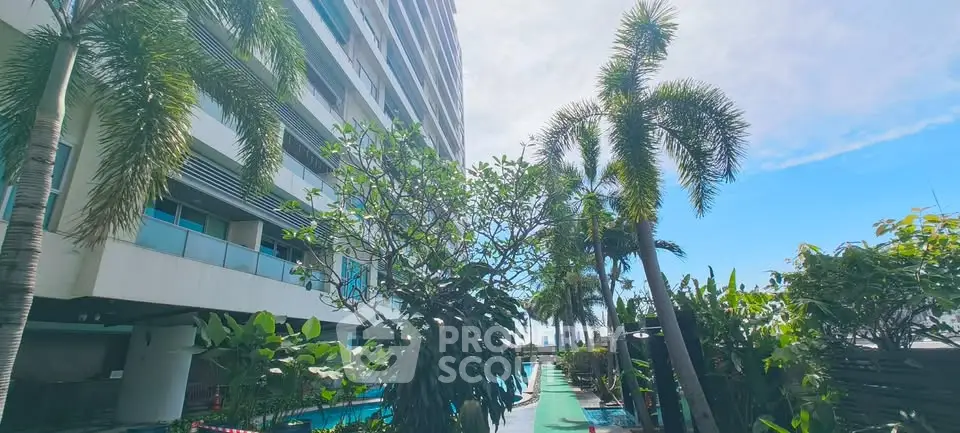 Luxurious high-rise building with lush garden and poolside view, perfect for urban living.