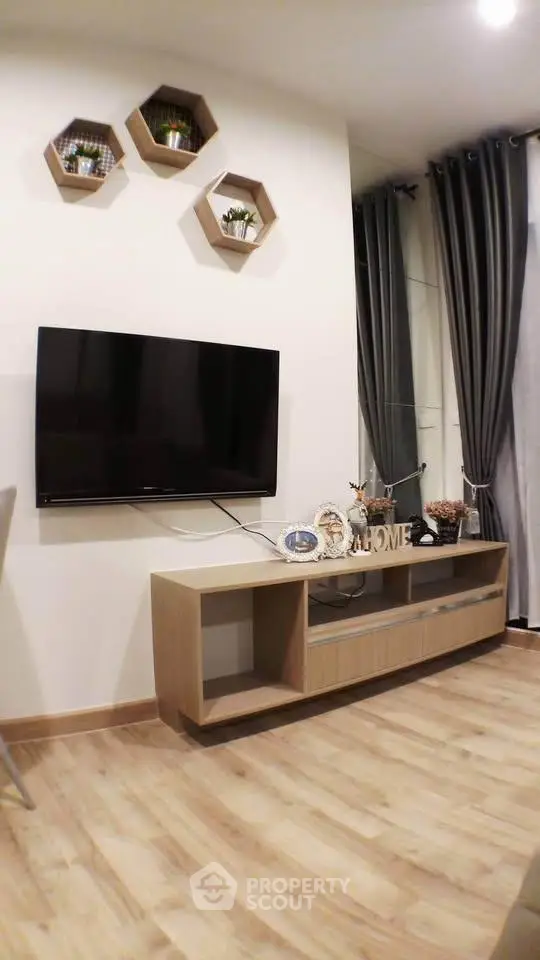 Modern living room with wall-mounted TV and stylish decor in a cozy apartment.