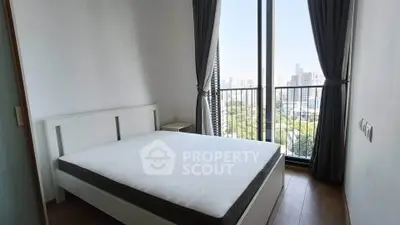 Modern bedroom with large window offering stunning city view and natural light.