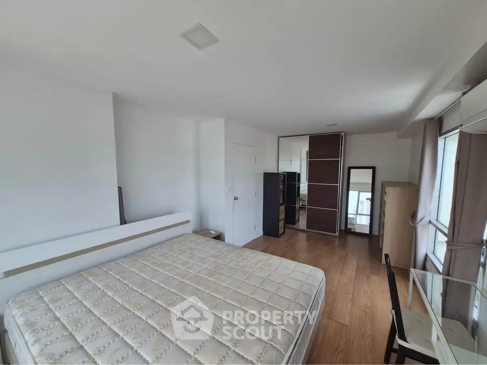 Spacious bedroom with modern furnishings and large windows for natural light.