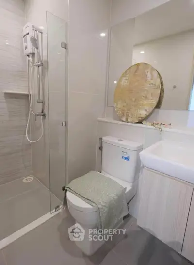 Modern bathroom with glass shower, sleek toilet, and stylish decor in a contemporary apartment.
