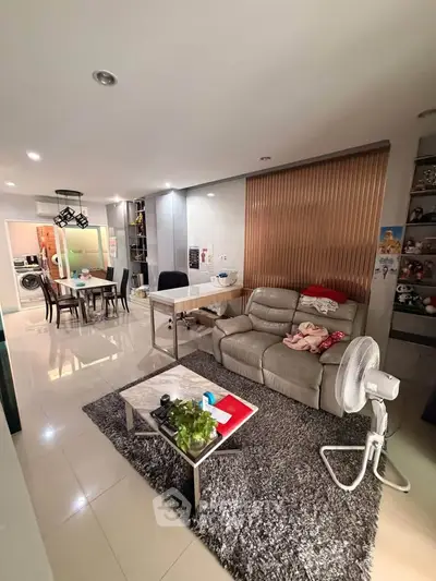 Modern living room with stylish decor and open dining area, featuring sleek furniture and ambient lighting.