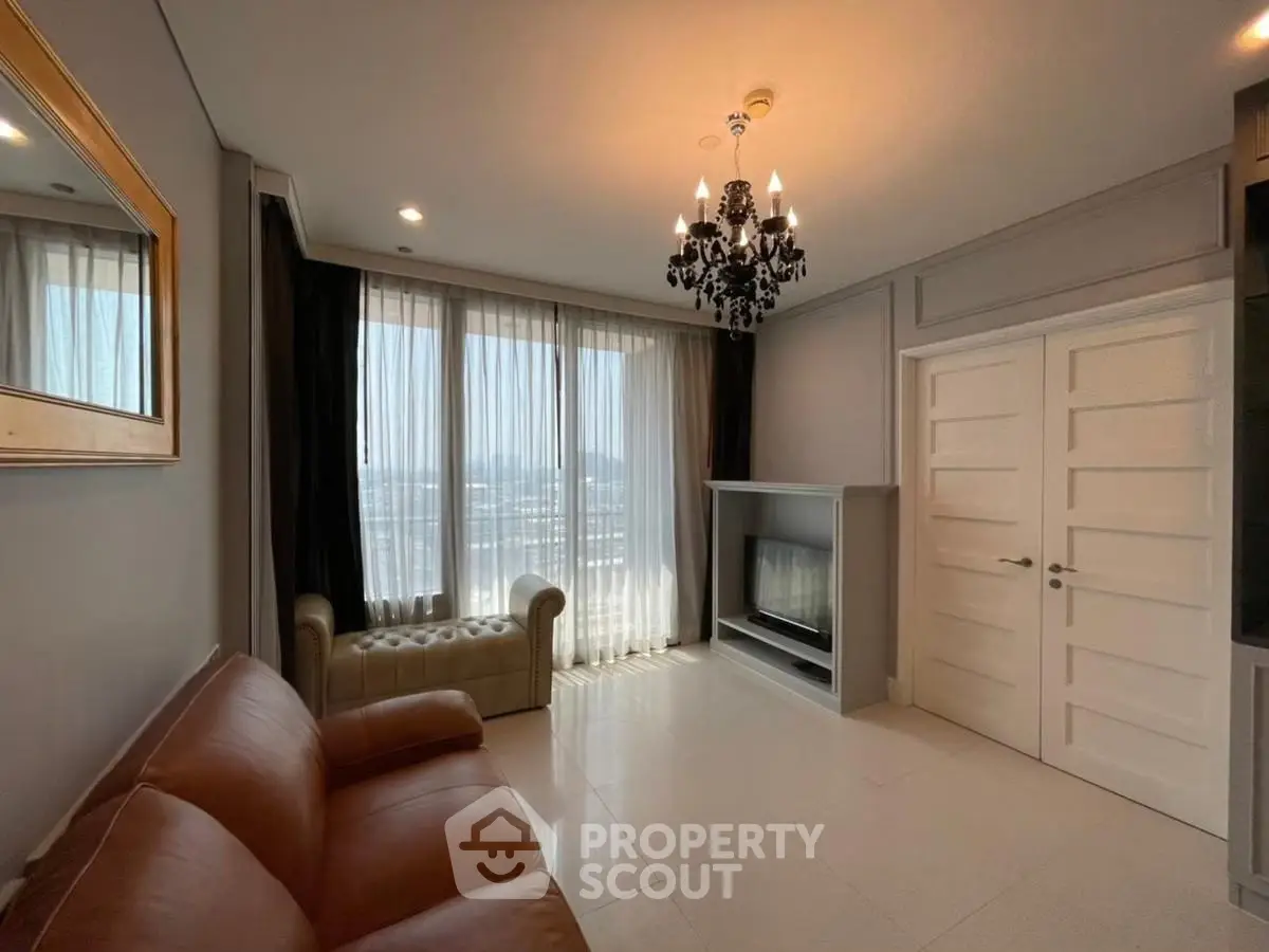 Elegant living room with chandelier, leather sofas, and large windows offering a stunning city view.