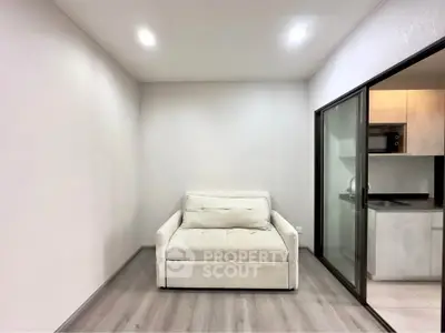 Modern minimalist living room with cozy sofa and sleek kitchen view