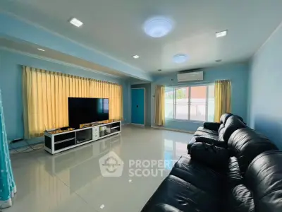Spacious living room with sleek leather sofas and large TV, perfect for relaxation.