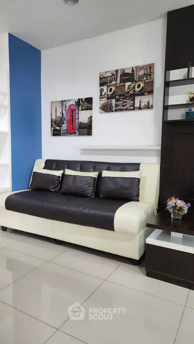Modern living room with stylish black and white sofa, wall art, and sleek shelving unit.