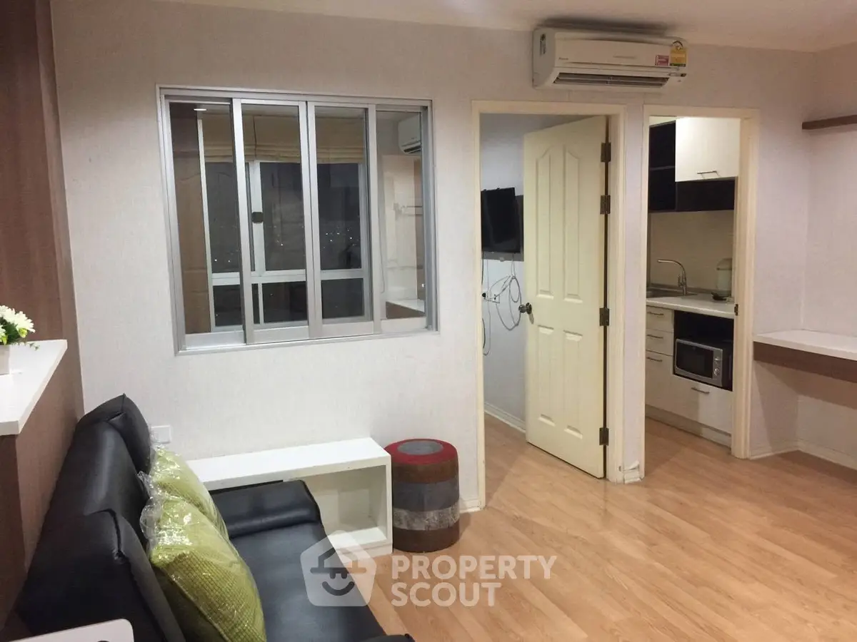 Modern apartment interior with open layout, featuring a cozy living room and compact kitchen.