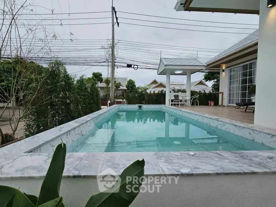 Stunning outdoor pool with elegant marble edging in a serene residential setting.