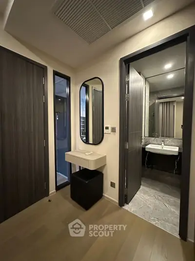 Modern apartment hallway with sleek bathroom entrance and stylish vanity mirror.