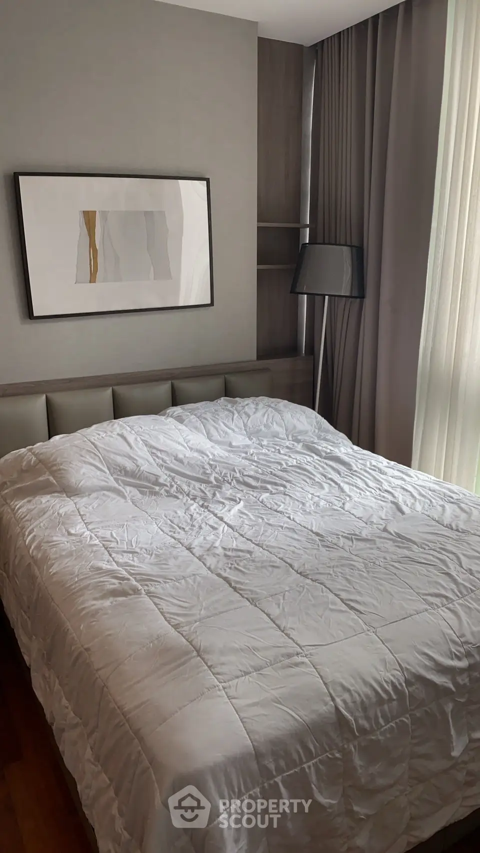 Modern bedroom with stylish decor and natural light, featuring a cozy bed and elegant artwork.