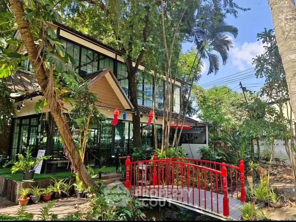 Charming garden view with modern glass building and red bridge