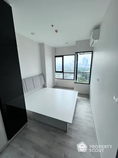 Sleek modern studio apartment with panoramic city views, featuring a cozy sleeping area, ample natural light, and a minimalist design, perfect for urban living.