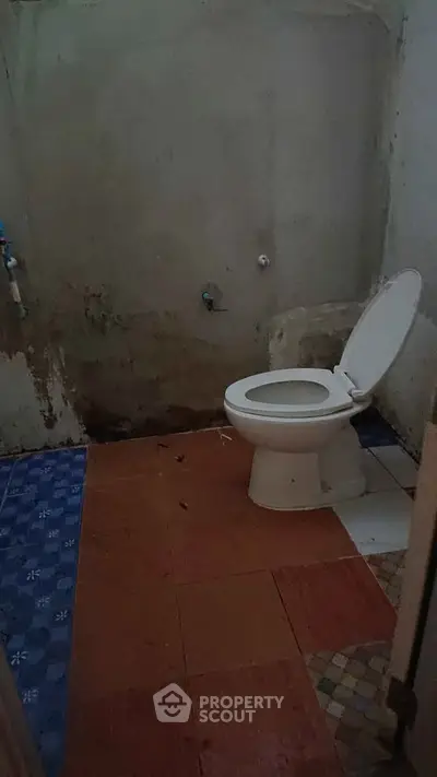 Basic bathroom with toilet and tiled floor, ideal for renovation project.