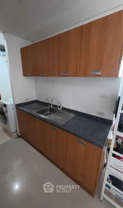 Modern kitchen with sleek cabinets and dual sink, adjacent to laundry area.