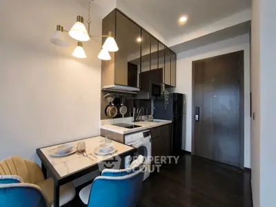 Modern kitchen with dining area, featuring washing machine and elegant lighting.