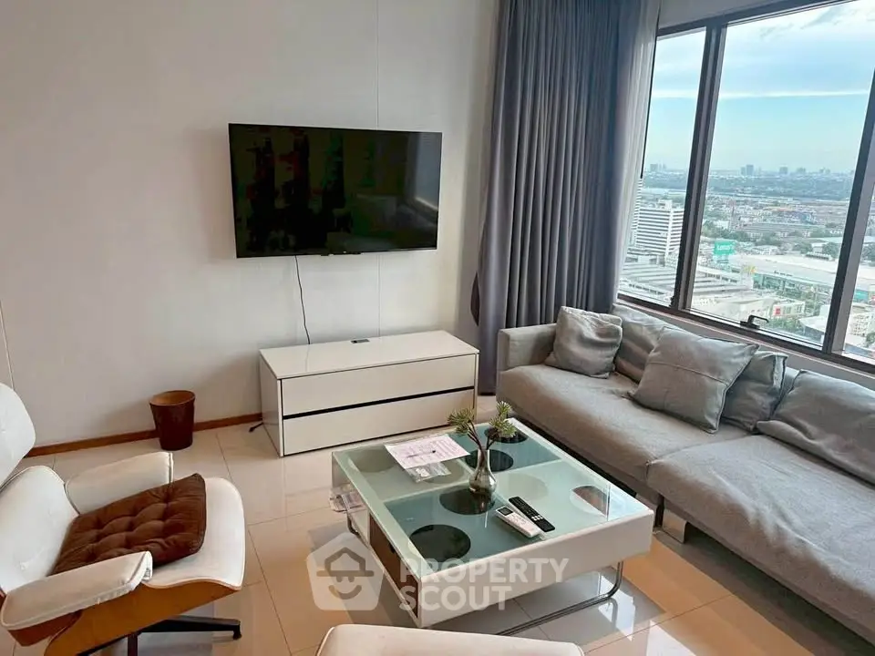 Modern living room with city view, stylish furniture, and wall-mounted TV in high-rise apartment.