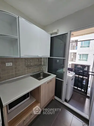 Modern kitchen with sleek cabinetry and balcony access in urban apartment