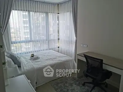 Modern bedroom with large windows and natural light, featuring a cozy bed and sleek desk.