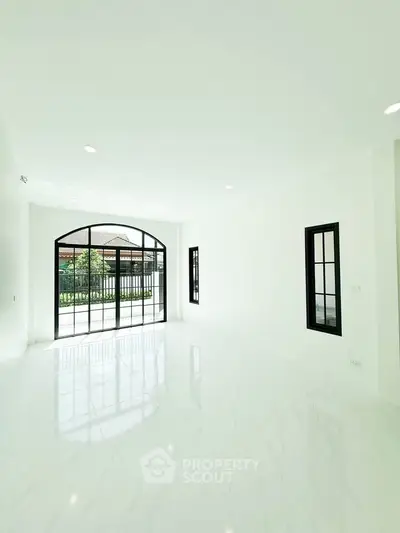 Spacious bright living room with large windows and glossy white flooring