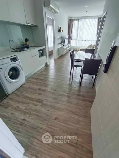 Modern apartment with open kitchen and living area featuring washing machine and dining table.