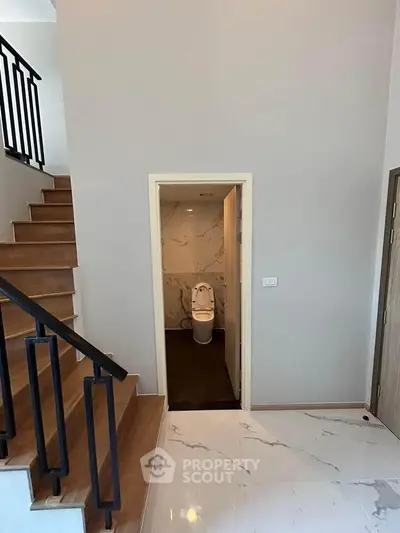 Modern home interior with staircase and bathroom entrance, featuring elegant marble flooring.