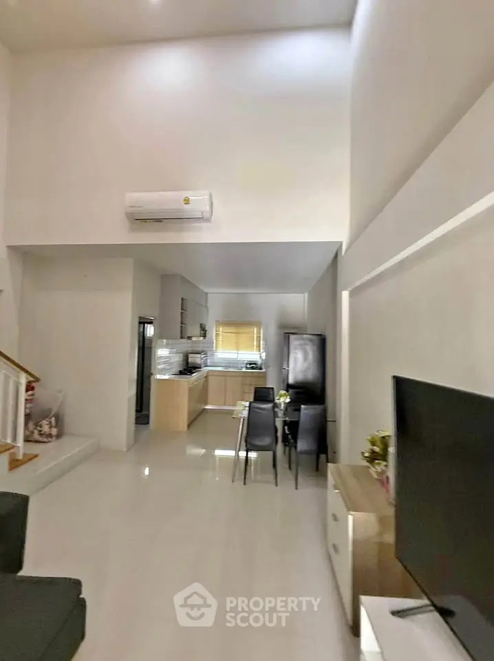 Modern open-plan living and dining area with sleek kitchen and high ceilings.