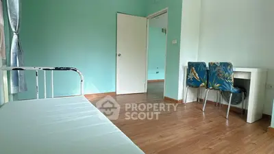 Spacious bedroom with wooden flooring and natural light, featuring a minimalist bed and study area.