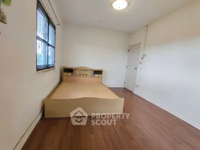 Spacious bedroom with wooden flooring and large window for natural light.