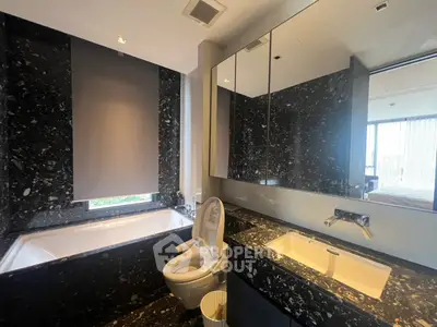 Luxurious modern bathroom with sleek black marble finish and elegant fixtures.