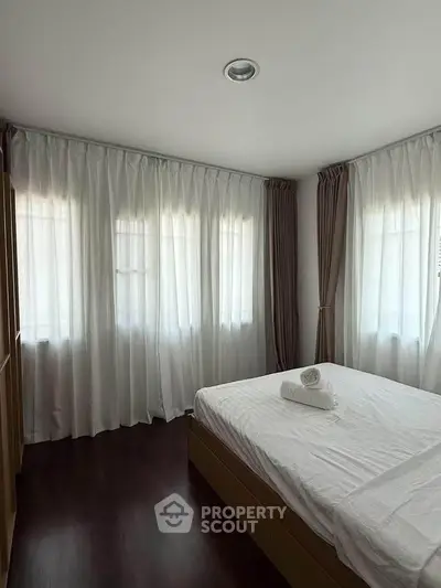 Bright and airy bedroom with large windows and elegant curtains, perfect for relaxation.