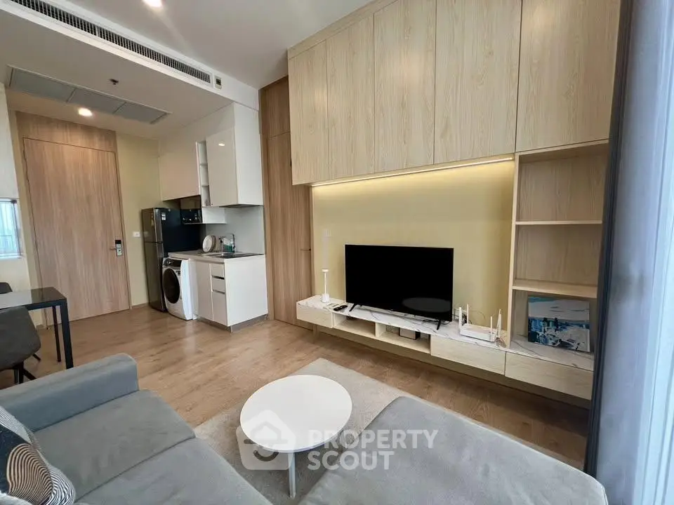 Modern living room with sleek furniture and integrated kitchen appliances in a stylish apartment.