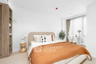 Modern bedroom with cozy decor and natural light, featuring a stylish bed and elegant furnishings.