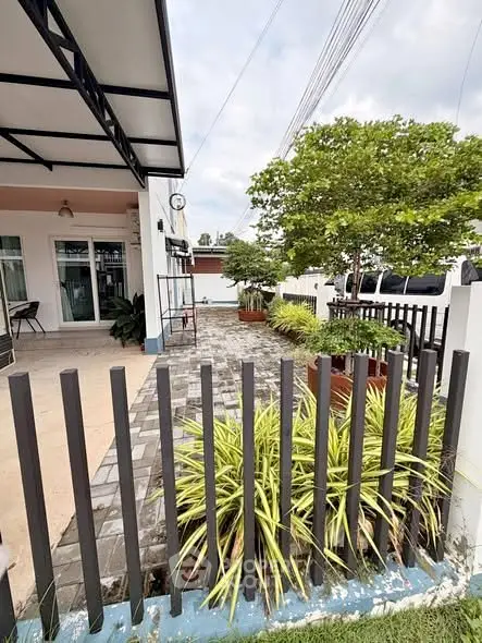 Charming house exterior with lush garden and paved patio area.