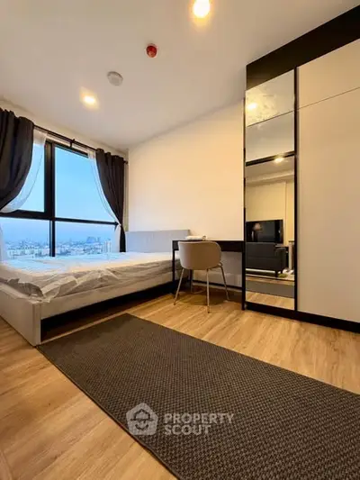 Modern bedroom with city view, sleek furniture, and wooden flooring in a high-rise apartment.